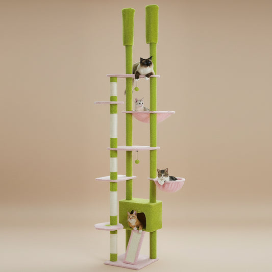 Green and white cat tree with multiple levels and a pink hammock on a beige background