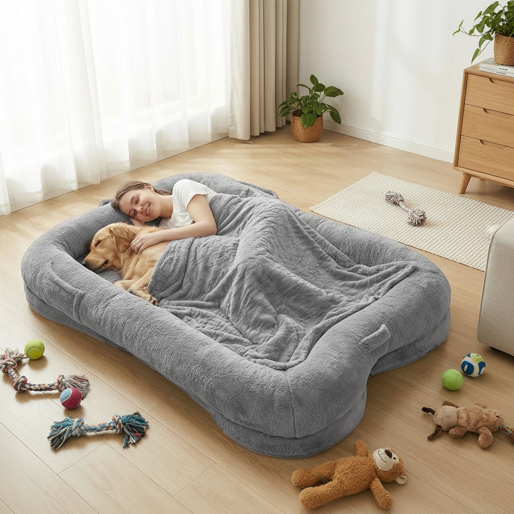 Woman and dog lying on a large gray pet bed with toys around them.