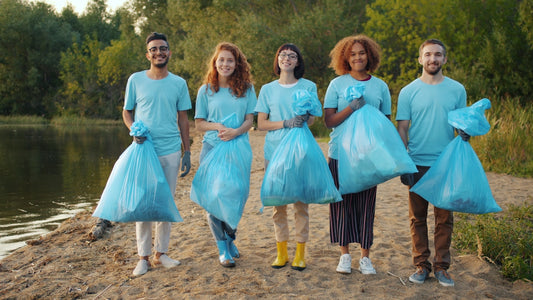 Diverse group of volunteers holding trash bags by water