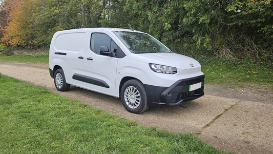 A white delivery van parked on a dirt road.