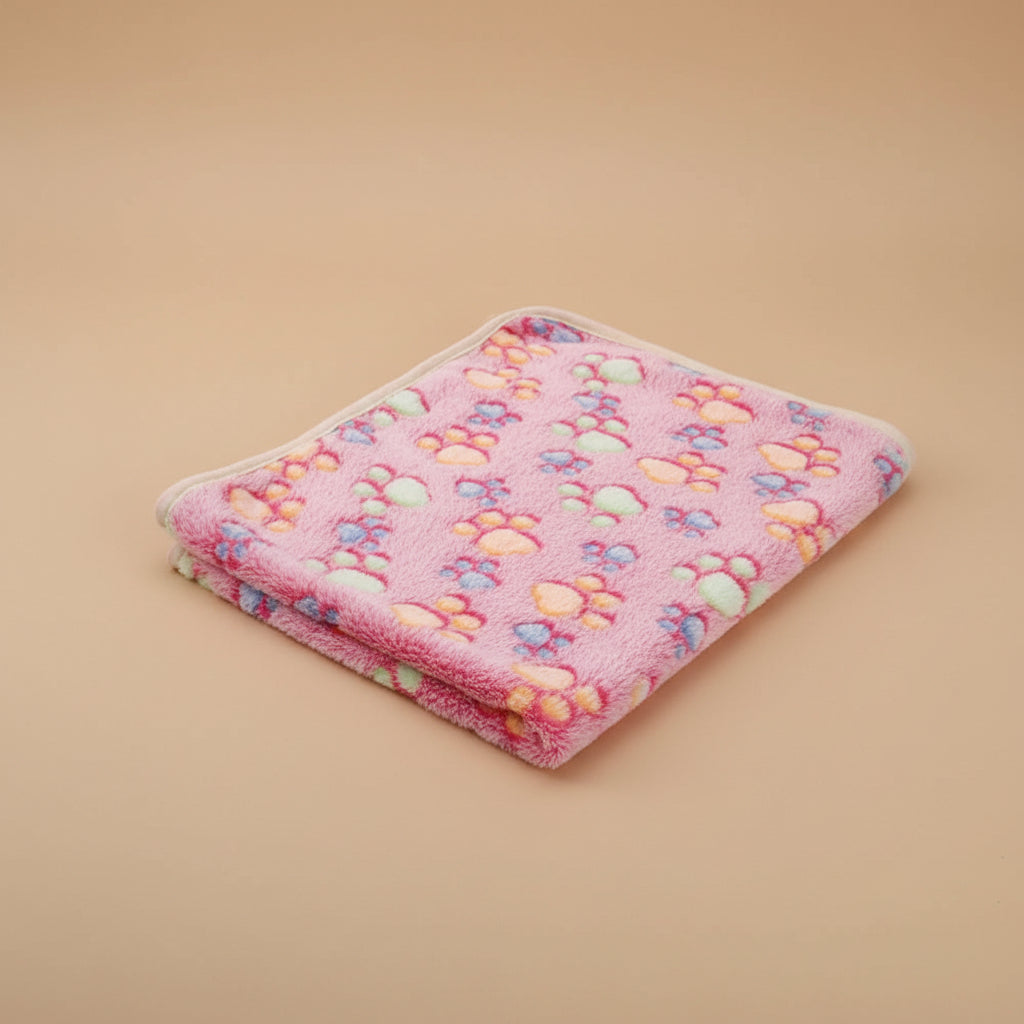 Pink pet blanket with colorful paw prints on a beige surface