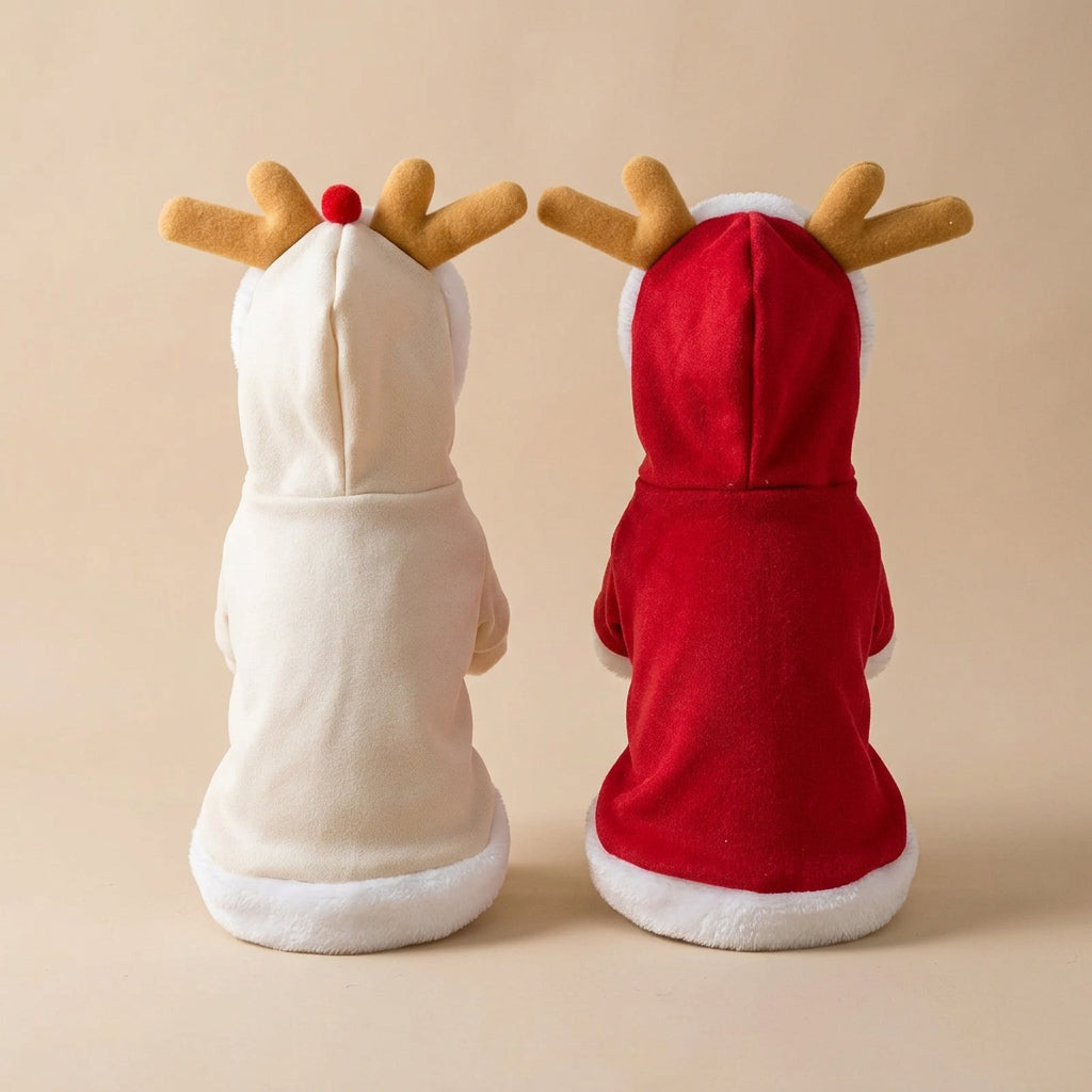 Back view of Two Christmas-themed plush reindeer cloaks laid flat on a light gray surface: one in cream with tan reindeer antlers and a one small red nose detail, and one in red with white faux-fur trim and tan antlers. 