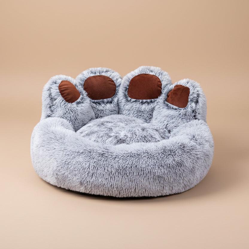 Plush paw-shaped pet bed with gray fur and brown pads on a white background