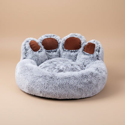 Plush paw-shaped pet bed with gray fur and brown pads on a white background