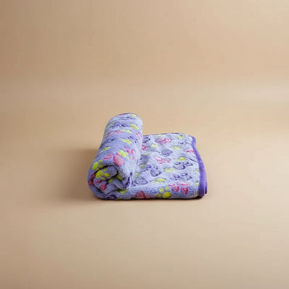 Purple pet blanket with paw prints on a tan background