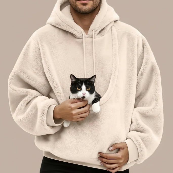 Person wearing a beige fleece hoodie with large pouch with a tuxedo cat inside.