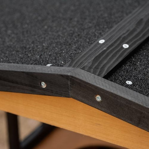 Close-up of a wooden product with black rubber strip and screws on a textured surface