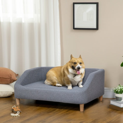 Dog sitting on a small gray sofa in a living room.