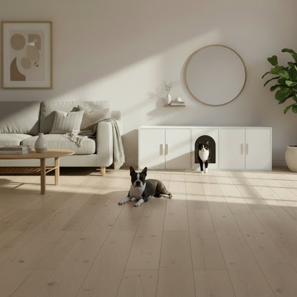 White cabinet with a pet door, cat inside, dog laying on floor and a plant on a wooden floor.