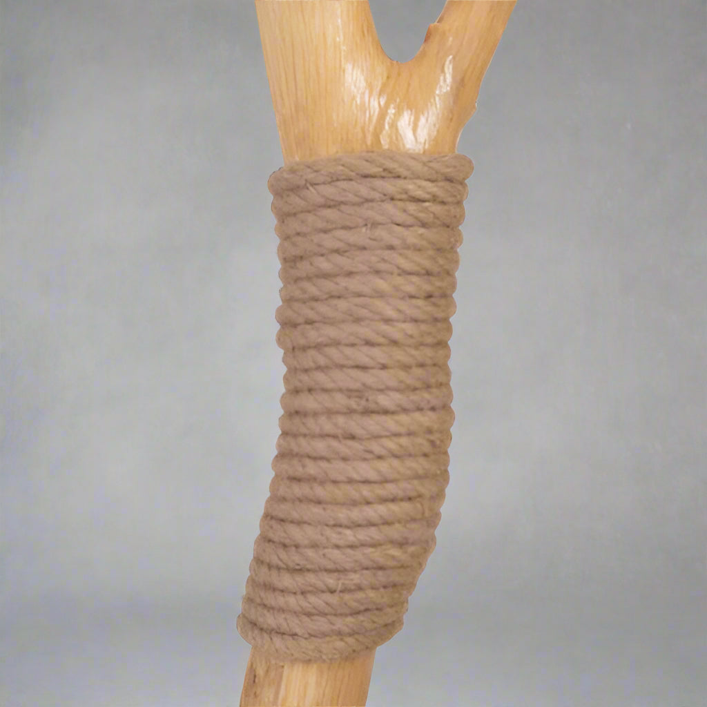 Wooden stick with brown rope wrapped around it on a white background