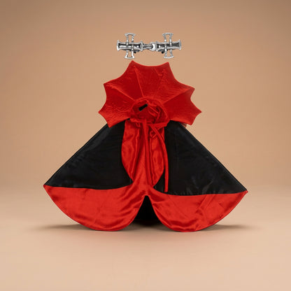 Black and red vampire cape with cross clip on a beige background.