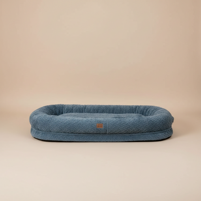 large blue pet bed with a beige studio background.