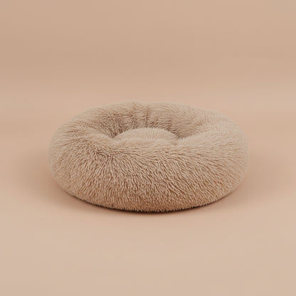 Fluffy beige pet bed on a white surface with a beige background