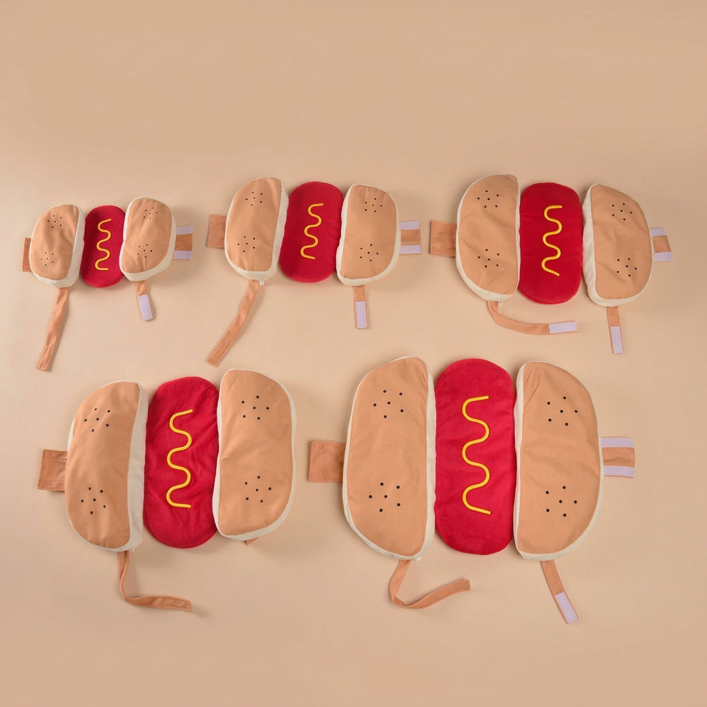 Hot dog-shaped costumes in different sizes, displayed on a beige background