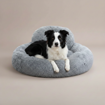 Dog lying on a gray fluffy donut bed with a visible brand logo.