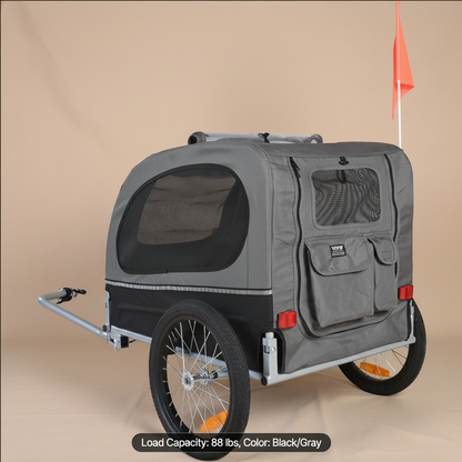 A gray and black pet trailer with mesh windows, two wheels, a silver trailer frame, and a small orange flag, shown on a beige background with a text overlay at the bottom.