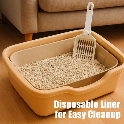 Cat litter box with disposable liner and scoop on a wooden floor.