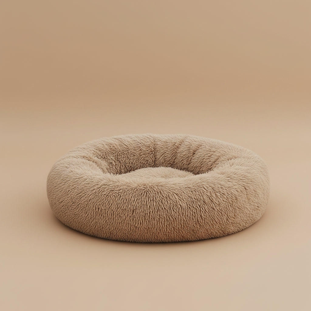 Dog lying on a fluffy beige donut bed on a beige background.