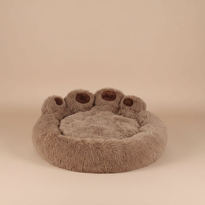 Round brown pet bed with bear paw design on a beige surface