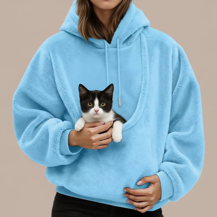 Person wearing a blue hoodie with a large pouch with a cat inside.