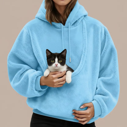 Person wearing a blue hoodie with a large pouch with a cat inside.
