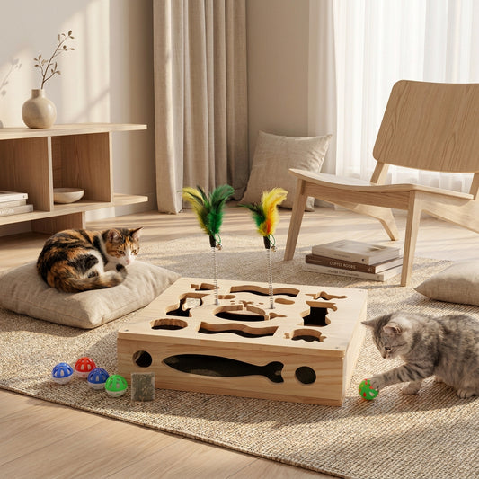 A wooden cat puzzle toy with nail file inside. Box has cutout shapes and two feather wands is shown with two cats interacting with it in a living room. Small colored balls and a small accessory are displayed along the bottom to insert inside the box to encourage play.